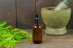 a bottle of essential oil next to a mortar and pestle