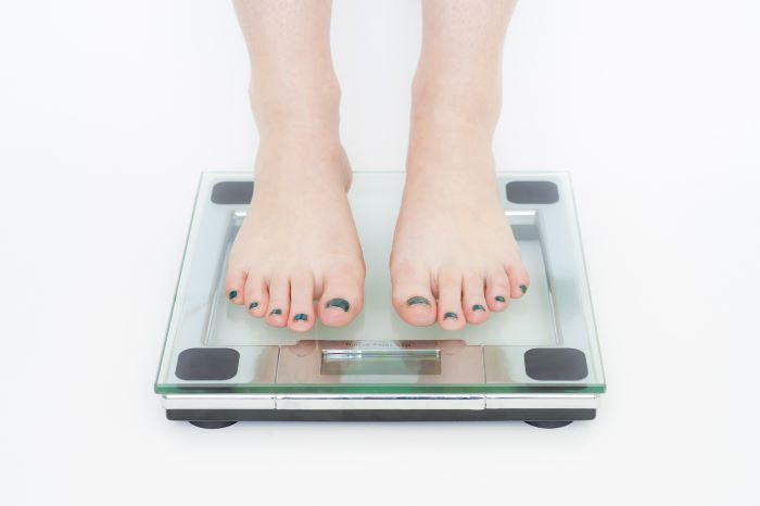 A Girl measuring her weight on weighing machine